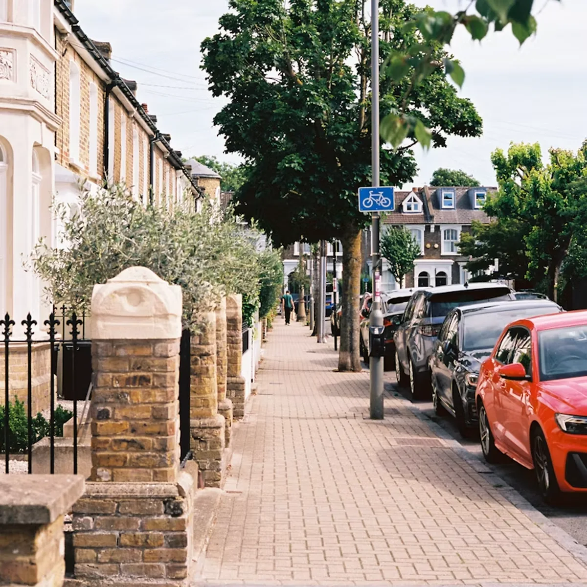 Residential street lined with homes, trees and parked vehicles